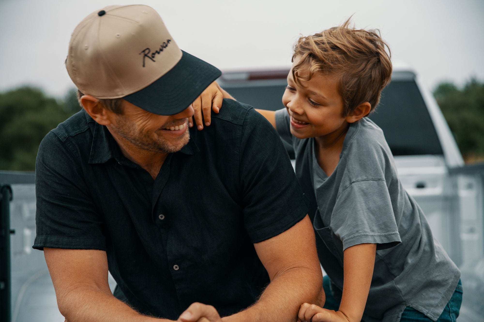 Man and child sitting together on a pickup truck bed