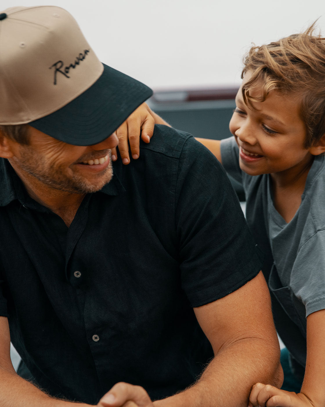 Man and child sitting together on a pickup truck bed